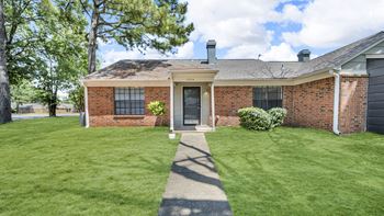 A red brick house with a green lawn in front.